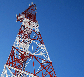 Red and white cellular tower with antennas against a clear blue sky, representing NB-IoT network connectivity and low-power wide-area communication technology.
